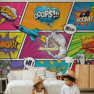 Peut inclure: Une murale colorée de style bande dessinée avec des mots d'action comme "ZAP!" et "BOOM!". Deux enfants portant des chapeaux sont assis sur un tapis, avec un chat à proximité. La pièce est décorée dans des tons neutres.