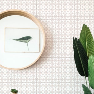 Peut inclure: Une commode blanche avec deux tiroirs et un dessus en bois. La commode est devant un mur avec un papier peint à motifs géométriques de couleur rose clair. Une petite plante en pot est posée sur le dessus de la commode. Un grand miroir rond est accroché au mur au-dessus de la commode. Une grande plante verte se trouve à droite de l'image.