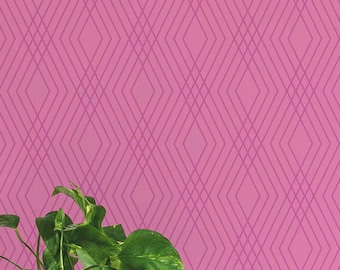 May include: A pink wallpaper with a geometric diamond pattern. A gold mirror with a decorative frame hangs on the wall. A potted plant, a tray with decorative items, and a stack of books are on a wooden table.
