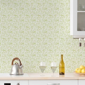 Puede incluir: Una cocina blanca con un papel tapiz floral verde claro. La cocina cuenta con una campana extractora blanca, un refrigerador blanco y gabinetes blancos. Hay una tetera de acero inoxidable en la encimera.