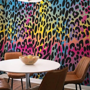 May include: A dining set featuring a white circular table, four brown leather chairs, and a colourful leopard print wallpaper in blue, yellow, pink, and black. A wooden bowl of fruit is on the table.