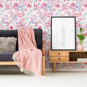 Pink Watercolor Botanical peel and stick wallpaper shows a soft botanical print on a wall behind a sofa.