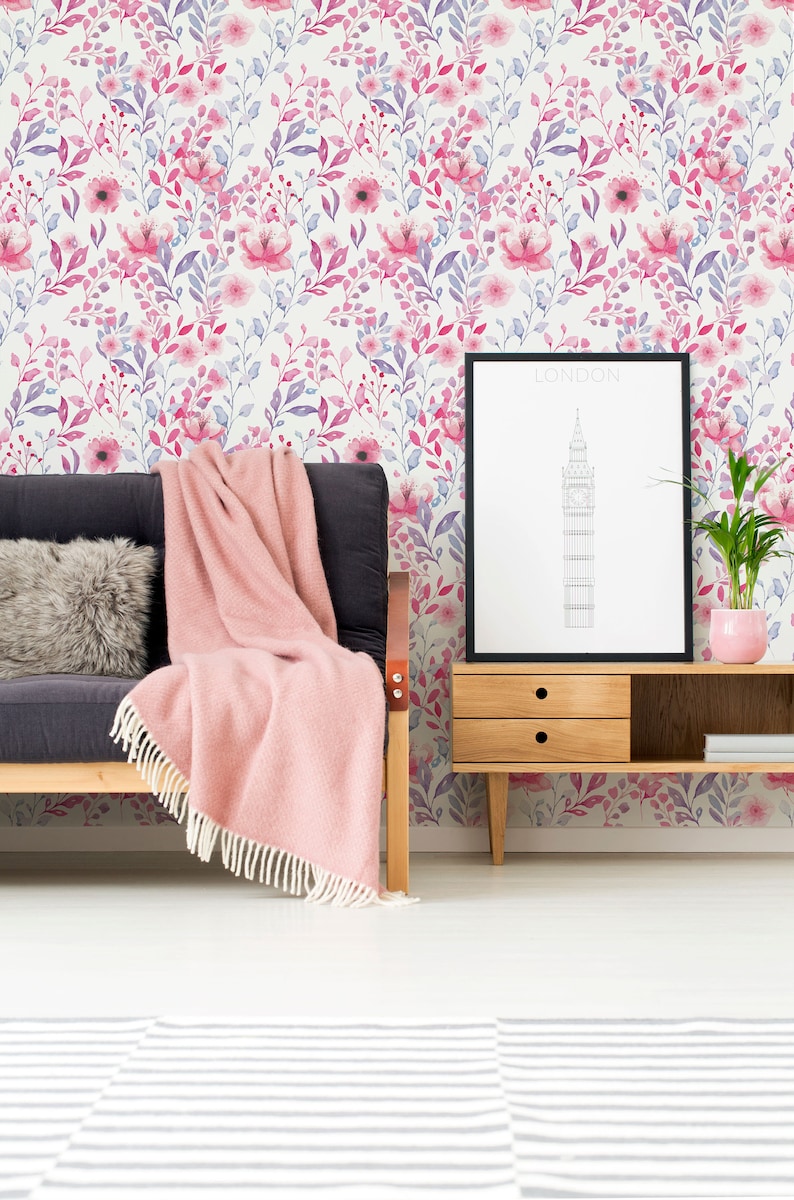 Pink Watercolor Botanical peel and stick wallpaper shows a soft botanical print on a wall behind a sofa.
