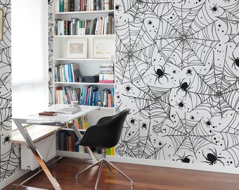 May include: A home office with a Halloween theme. The walls are decorated with a black and white spiderweb pattern. A white desk, black chair, and bookshelf are in the room. The floor is made of dark wood.