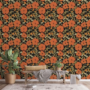 May include: A black background with a repeating pattern of orange flowers. A wooden bench with a brown throw blanket is in front of the wall. A potted plant is on the left side of the bench and a potted plant and a wicker basket are on the right side of the bench.