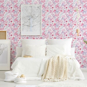 Pink Watercolor Botanical self-adhesive wallpaper shows a soft floral look on a bedroom wall behind a white bed.