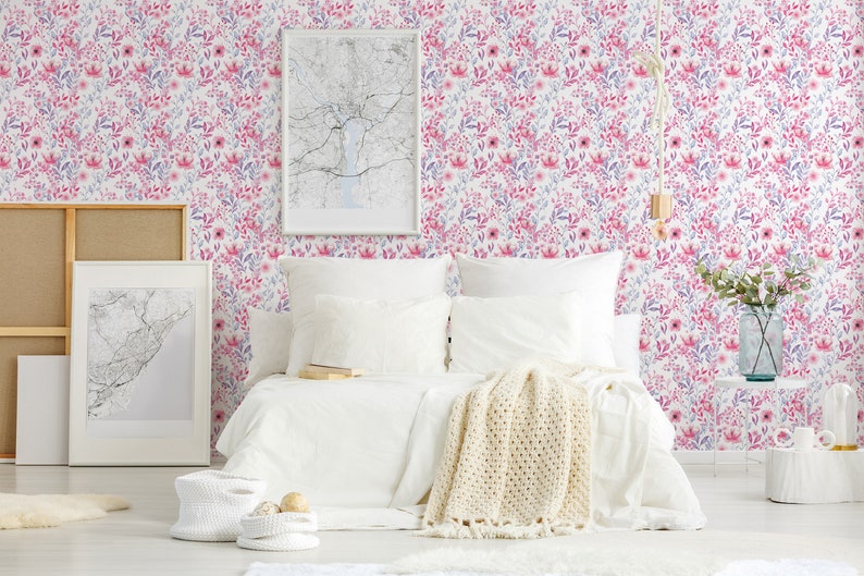 Pink Watercolor Botanical self-adhesive wallpaper shows a soft floral look on a bedroom wall behind a white bed.
