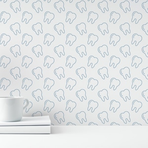Può includere: Un bancone bianco con una tazza bianca e due libri bianchi impilati uno sopra l'altro. Dietro il bancone, una parete bianca con un motivo a denti blu.