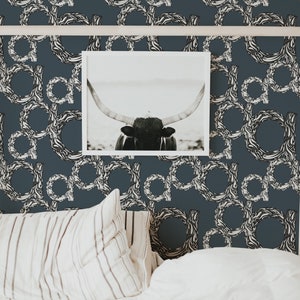 May include: A bedroom interior with a white headboard and a framed black and white photograph of a longhorn bull. The walls are covered in a dark blue wallpaper with a white abstract pattern.