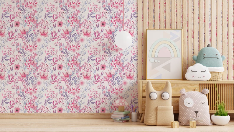 Pink Watercolor Botanical peel and stick wallpaper shows a soft floral wall in a nursery, with a wooden dresser.