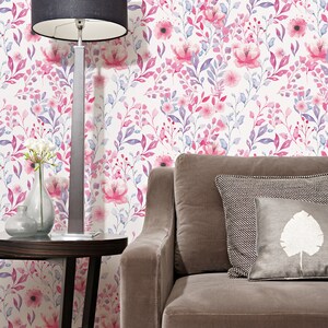 Pink Watercolor Botanical peel and stick wallpaper shows a soft floral wall design beside a gray sofa.