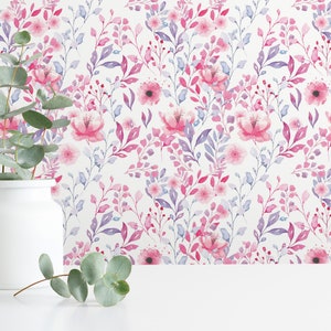 Pink Watercolor Botanical peel and stick wallpaper shows a soft floral and leafy design on a wall behind a white vase.