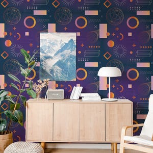 May include: A dark purple wallpaper featuring a repeating pattern of orange gradient circles, wireframe spheres, rectangles, and geometric symbols. A rectangular print of a snow-covered mountain range is displayed on the wall above a wooden sideboard.