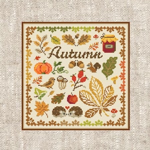 May include: Cross-stitch design with an autumnal theme. The word "Autumn" is central, surrounded by leaves, a pumpkin, acorns, a squirrel, a bird, a mushroom, an apple, and a jar of jam. The design is framed with a brown border.