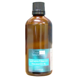 May include: A brown glass bottle with a black cap, containing a fragrance oil. The label is blue and white and reads "Fresh Skin" and "Leather & Tobacco Fragrance Oil".