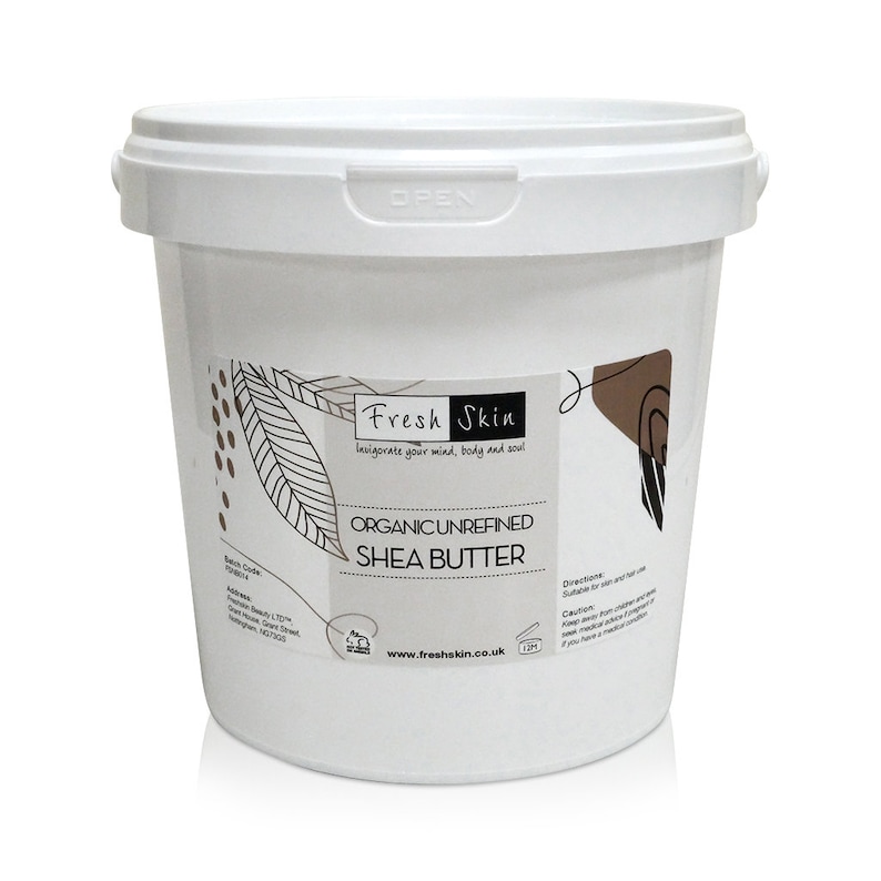Op de afbeelding: Een witte plastic emmer met een deksel met daarin ongeraffineerde biologische sheaboter. Het etiket is wit met zwarte tekst en een bruin grafisch ontwerp. De tekst op het etiket luidt "Fresh Skin", "Invigorate your mind, body and soul", "Organic Unrefined Shea Butter", "www.freshskin.co.uk", "Directions", "Suitable for skin and hair use", "Caution", "Keep away from children", "If you are pregnant or breastfeeding, seek medical advice before use", "If you have a medical condition..."