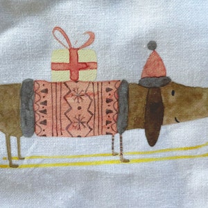 May include: A brown dachshund wearing a pink and gray sweater and a red Santa hat is carrying a wrapped gift on its back. The dachshund is standing on yellow skis on a white background.