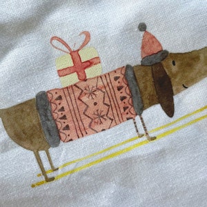 May include: A brown dachshund wearing a pink and gray sweater and a red Santa hat is skiing with a yellow present on its back.