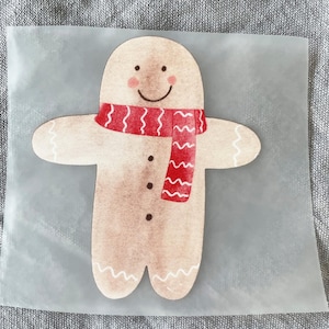 Op de afbeelding: Een gingerbread man met een rood-wit gestreepte sjaal, op een transparante achtergrond.