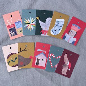 K&ouml;nnte beinhalten: Eine Sammlung farbenfroher Weihnachtsetiketten mit verschiedenen festlichen Illustrationen. Designs umfassen Geschenkpakete, einen Stern, eine Maus mit Stern, einen Strumpf, einen Nussknacker, eine Kugel, ein Rentier, ein Haus, Zuckerstangen und einen Dackel.