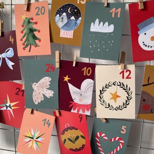 May include: A collection of rectangular advent calendar cards featuring various holiday illustrations including a Christmas tree, snowman, bird, mouse, wreath, and candy canes, each marked with a unique number and clipped to a wire grid.