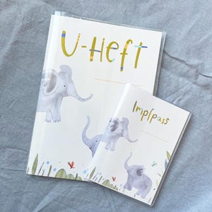 May include: Two clear plastic covered folders with a white background and colourful elephant illustrations. The larger folder has the text "U-Heft" in yellow. The smaller folder has the text "Impfpass" in black.