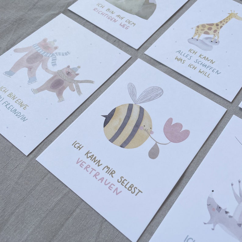 Op de afbeelding: Set van 6 ge&iuml;llustreerde affirmatiekaarten met aquarel-dierillustraties en positieve boodschappen in het Duits. De kaarten tonen een bij, een giraffe, twee beren, een egel en een vogel. De boodschappen omvatten "Ich bin auf dem richtigen Weg", "Ich kann alles schaffen was ich will", "Ich bin ein/e Freund/in", "Ich kann mir selbst vertrauen" en meer.