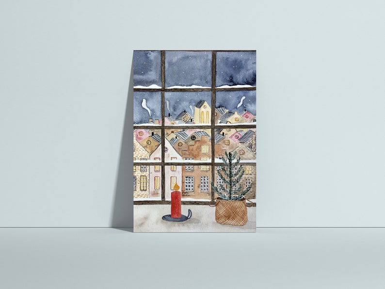 Puede incluir: Una pintura de acuarela de una ventana con vista a un pueblo nevado de noche. Una vela encendida y un peque&ntilde;o &aacute;rbol de Navidad en maceta est&aacute;n en el alf&eacute;izar de la ventana.