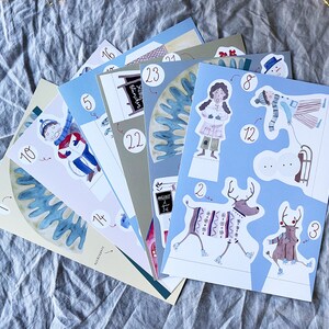 May include: A set of colorful paper cutouts featuring winter scenes and characters. The cutouts include a snowman, reindeer, a person wearing a winter coat, and a person wearing a red and white striped sweater. The cutouts are numbered 1 through 12.