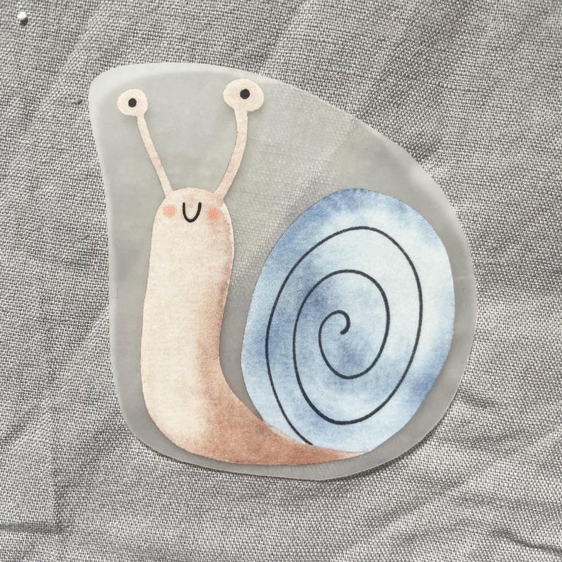 Pu&ograve; includere: Un adesivo stravagante con una lumaca dei cartoni animati con un corpo rosa chiaro e un guscio a spirale blu e bianco. La lumaca ha lunghe antenne con occhi neri e una faccia sorridente. L'adesivo &egrave; su sfondo grigio.