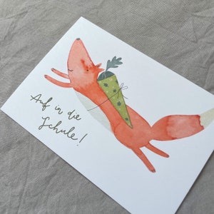 May include: A watercolour illustration of a red fox carrying a green and white cone with the text "Auf in die Schule!" on a white background.