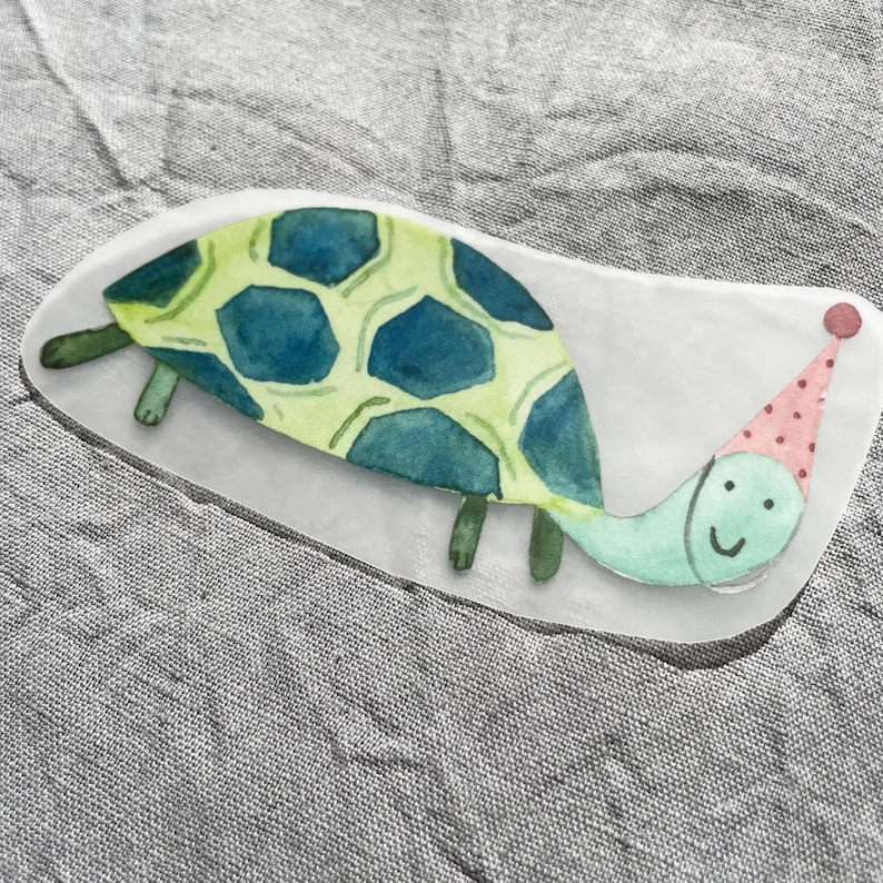 May include: A green and blue watercolor illustration of a turtle wearing a pink and white polka dot party hat. The turtle has a smiling face.