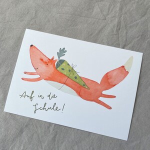 May include: A watercolour illustration of a red fox with a green and brown cone on its back. The fox is flying through the air with its tail outstretched. The text "Auf in die Schule!" is written below the fox.