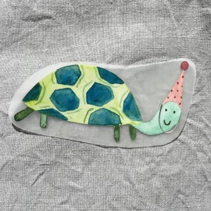May include: A watercolor painting of a green turtle wearing a pink and white party hat. The turtle has a blue shell with green accents.