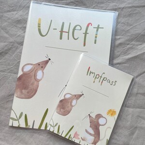 May include: Two protective covers for documents, one larger and one smaller, both made of clear plastic. The larger cover features a brown mouse illustration and the text U-Heft. The smaller cover shows two brown mice and the text Impfpass.