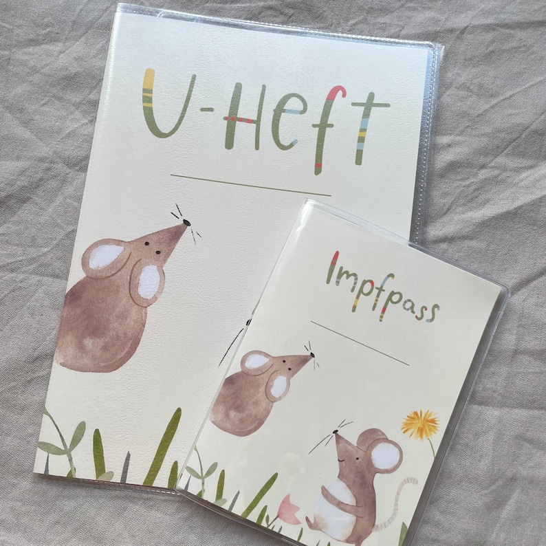 May include: Two protective covers for documents, one larger and one smaller, both made of clear plastic. The larger cover features a brown mouse illustration and the text U-Heft. The smaller cover shows two brown mice and the text Impfpass.