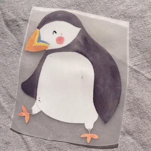 Può includere: Illustrazione ad acquerello di una pulcinella di mare. L'uccello ha un ventre bianco, dorso e ali neri e una testa bianca con un berretto nero. Il suo becco è arancione e giallo e ha piccoli piedi arancioni. La pulcinella di mare ha un'espressione allegra con guance rosee.