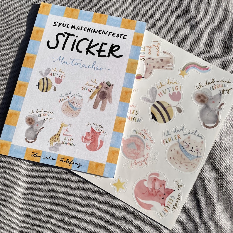 K&ouml;nnte beinhalten: Ein Aufkleber-Set mit verschiedenen Aquarellillustrationen von Tieren und S&auml;tzen auf Deutsch. Die Aufkleber zeigen eine Biene, eine Maus, eine Katze, einen Fuchs und einen B&auml;ren. Das Set tr&auml;gt den Titel "SP&Uuml;LMASCHINEN FESTE STICKER - Mutmacher-".
