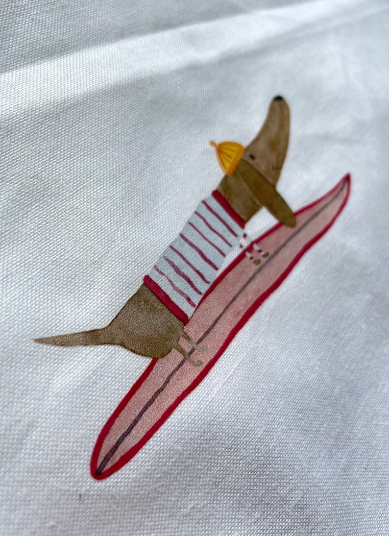 May include: A brown dachshund wearing a striped shirt and a yellow hat is riding a pink surfboard with red trim.