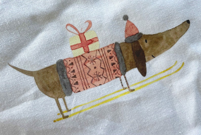 May include: A brown dachshund wearing a pink and gray sweater and a red Santa hat is skiing with a yellow present on its back.