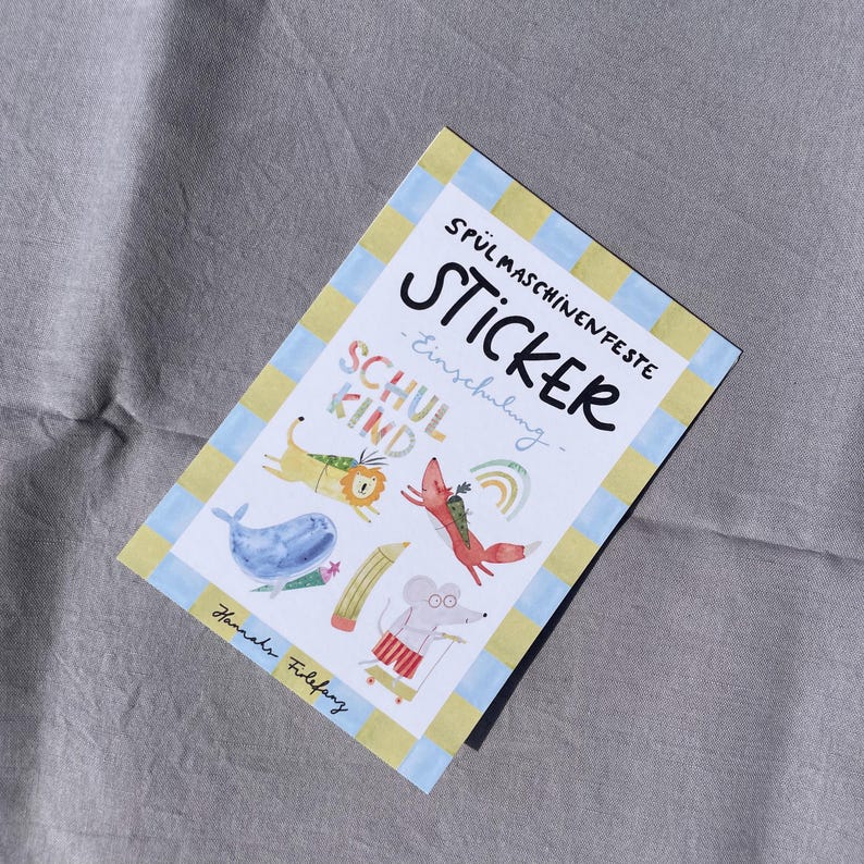 Pu&ograve; includere: Un foglio di adesivi con un bordo blu e giallo, con illustrazioni fantasiose di animali e un arcobaleno. La parola "STICKER" &egrave; ben visibile, insieme al testo "SCHUL KIND" e "Einschulung". Il foglio di adesivi &egrave; su una superficie grigia.
