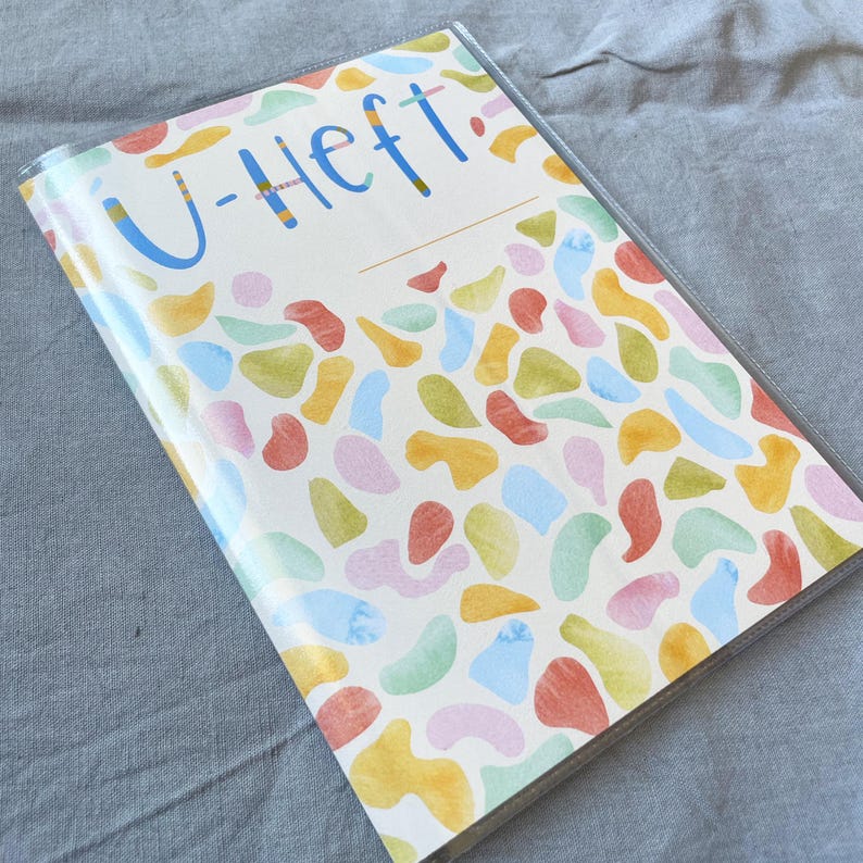 May include: A white binder with a colorful abstract pattern and the text "U-Heft" in blue.