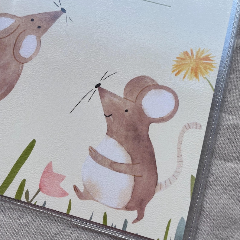 May include: A watercolor illustration on a light cream background featuring two brown mice with white bellies. One mouse stands upright near a yellow dandelion and a pink flower, while the other mouse is partially visible in the upper left corner.