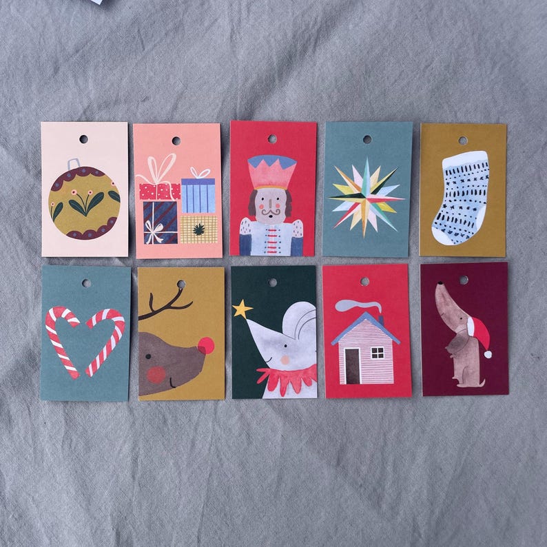 K&ouml;nnte beinhalten: Zehn weihnachtliche Geschenkanh&auml;nger mit verschiedenen Illustrationen. Sie zeigen eine Christbaumkugel, Geschenke, einen Nussknacker, einen Stern, einen Strumpf, ein Zuckerstangenherz, ein Rentier, eine Maus, ein Haus und einen Dackel mit Weihnachtsm&uuml;tze.