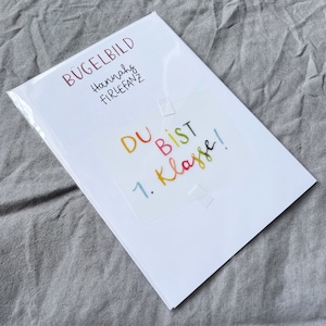 Może przedstawiać: Biała kartka z tekstem "B&uuml;gelbild Hannahs Firlefanz" i kolorową naklejką z napisem "Du bist 1. Klasse!"