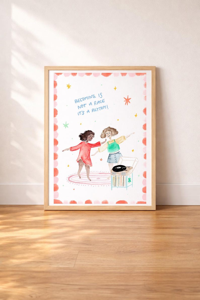 May include: Watercolor art print in a wooden frame. The artwork features two dancing figures, a record player, and the text "Becoming is not a race it's a rhythm!" The border has a pink and red dotted design with stars.