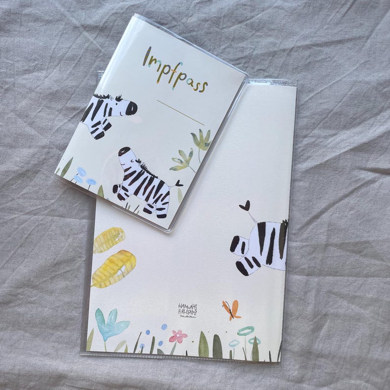 May include: A clear plastic protective cover containing a vaccination record booklet labelled Impfpass and a matching document folder. Both items feature watercolour illustrations of zebras, green leaves, blue flowers, and a small orange butterfly.