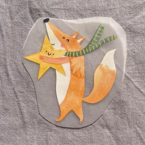 Op de afbeelding: Een grillige illustratie van een vos die een gele ster omhelst. De vos is oranje en wit en draagt een groen-gele gestreepte sjaal. De ster heeft een lachend gezicht. De afbeelding heeft een aquarel stijl.