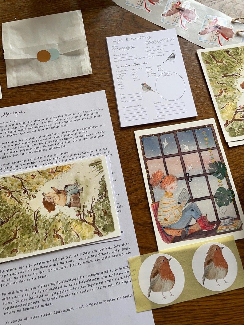 Op de afbeelding: Een verzameling ge&iuml;llustreerde briefpapierartikelen, waaronder ansichtkaarten, stickers en een notitieblok met vogelillustraties. Het kunstwerk toont een gezellige sc&egrave;ne van een persoon die bij een raam leest en een aquarel van een vogel.