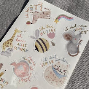 K&ouml;nnte beinhalten: Ein Bogen mit Aufklebern mit Aquarellillustrationen von Tieren und motivierenden S&auml;tzen. Die Aufkleber zeigen eine Giraffe, eine Biene, eine Maus, eine Katze und einen Hund, jeweils mit einem einzigartigen Design und einer Sprechblase.
